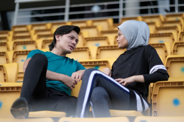 Two people talking in stadium chairs