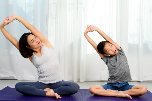 Woman doing yoga with her son.