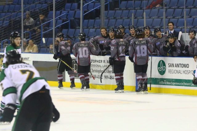 Hockey team is shown skating past their bench high-fiving in celebration