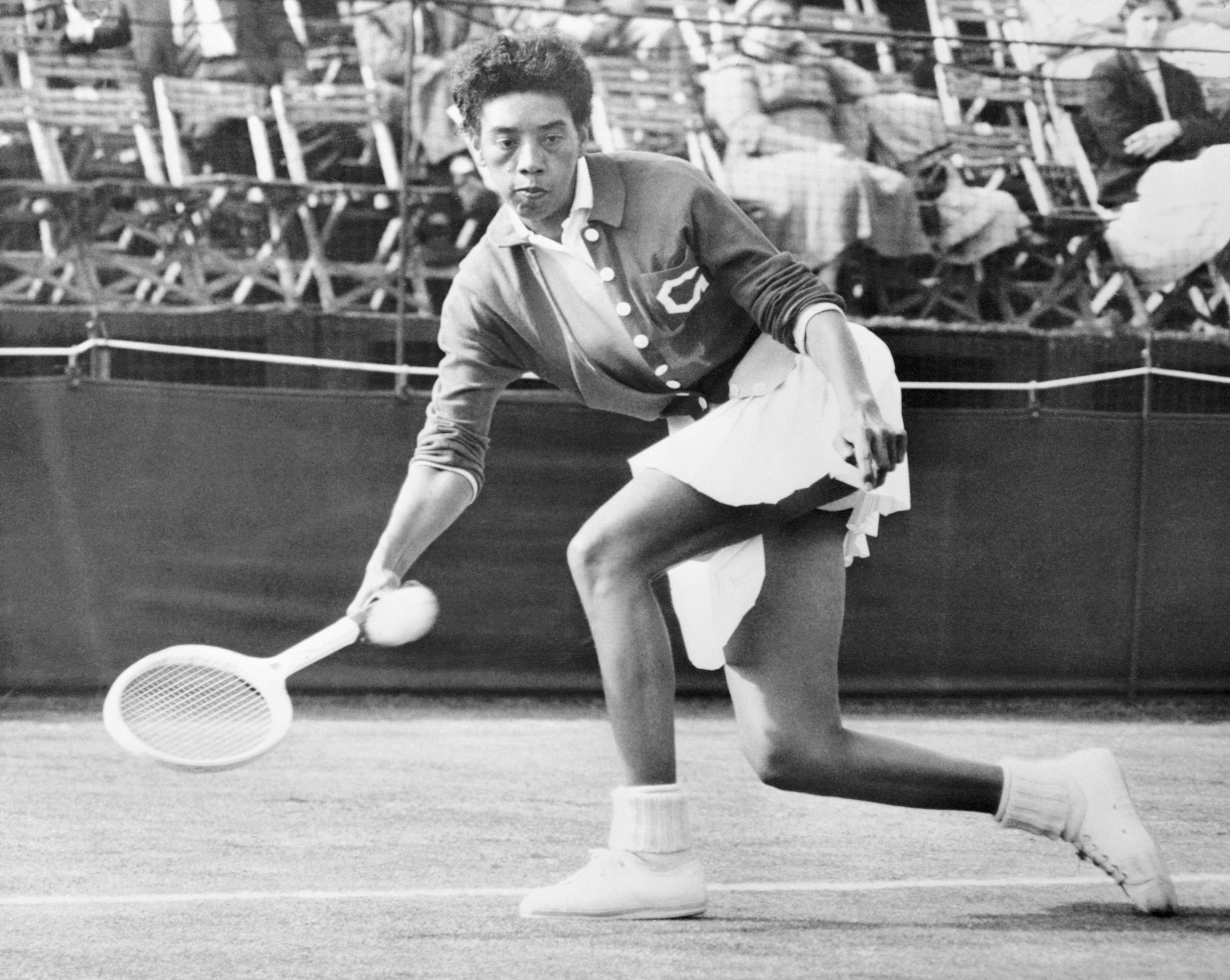 Althea Gibson reaching for a tennis ball with her tennis racket during a match