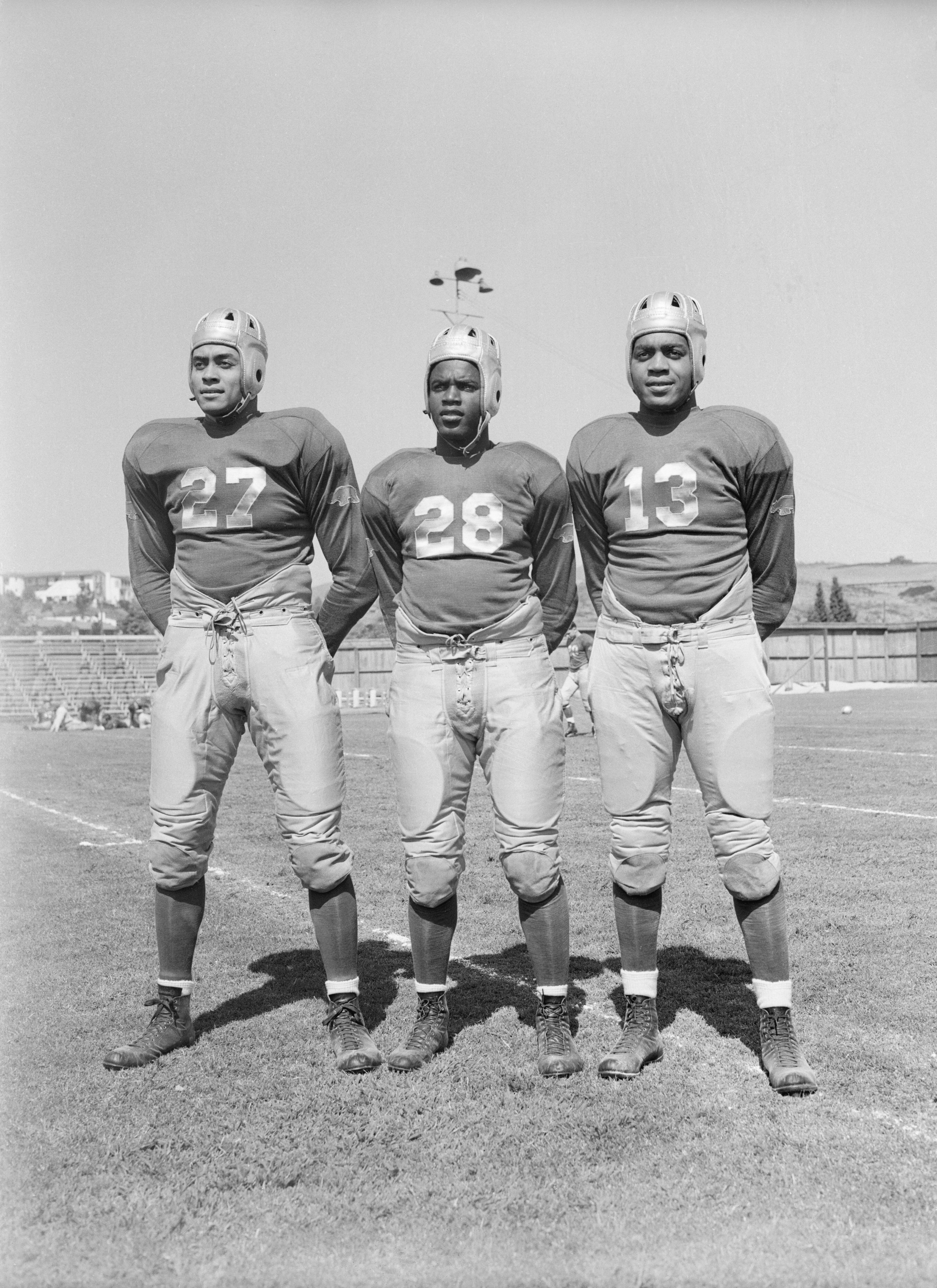  Woody Strode, Jackie Robinson, and Kenny Washington on the football field in their UCLA uniforms
