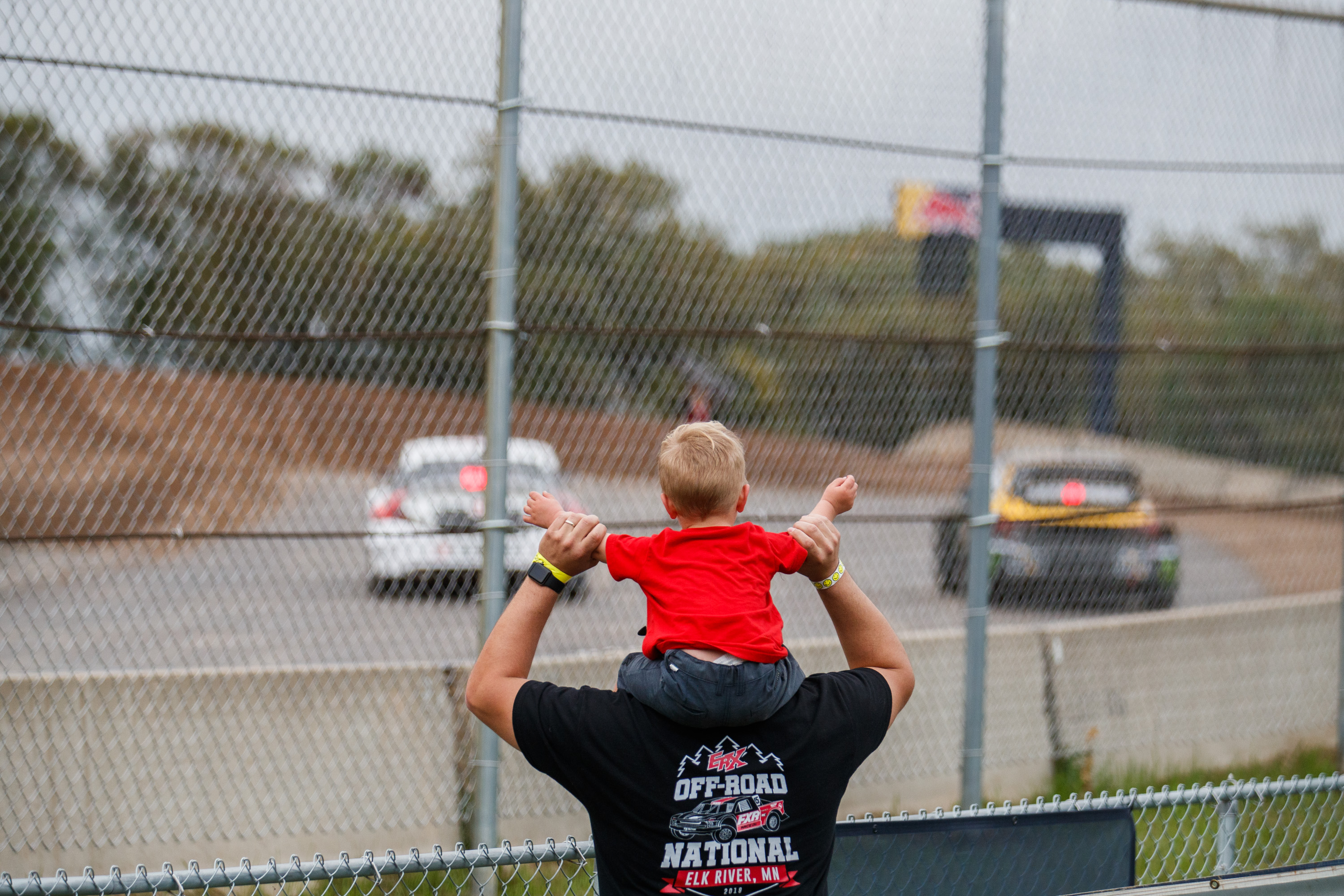 Dad with kid on shoulders at Nitro RX race.