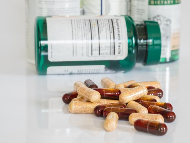 Vitamin bottle with stack of vitamins on counter. 