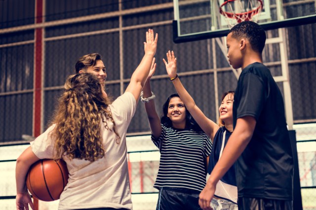 Group of teenager friends on a basketball court giving each other a high five