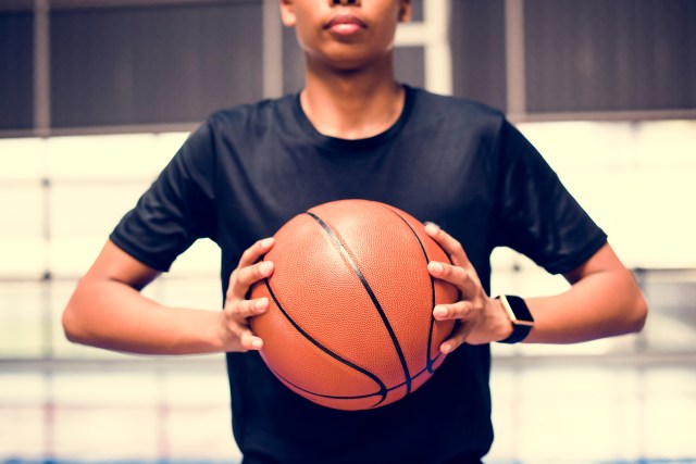 Teenage boy holding a basketball on the court