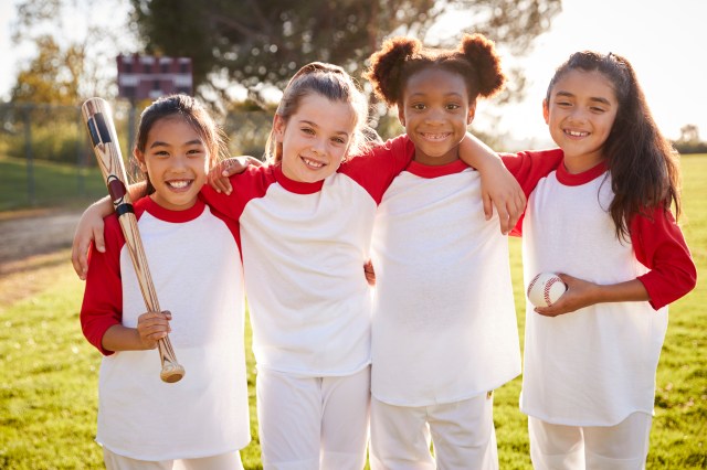 Schoolgirl baseball team holding baseball, portrait