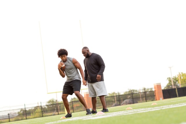 American football coach training an athlete.