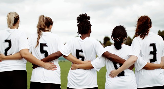 Female soccer players huddling and standing together
