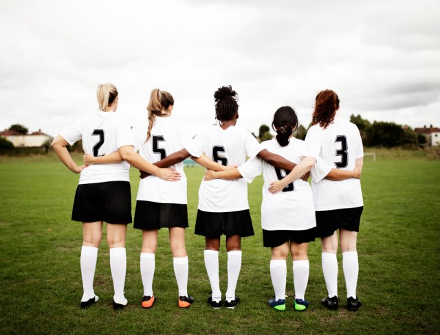 Female soccer players huddling and standing together
