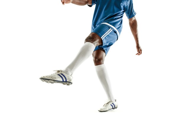 The legs of soccer player close-up isolated on white. African american model in action or movement with ball. The football, game, sport, player, athlete, competition concept