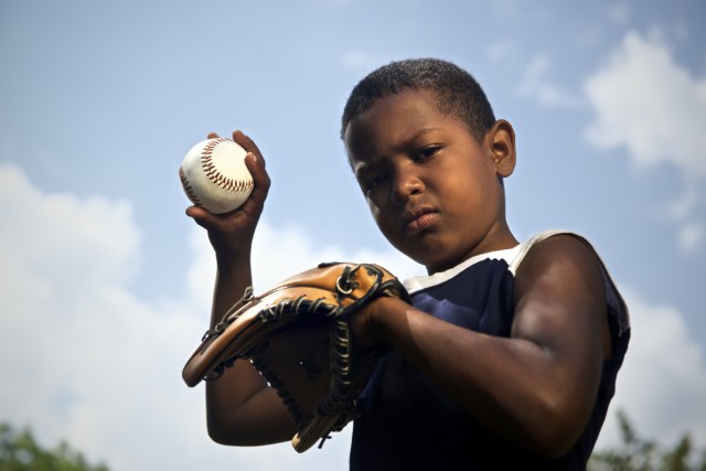 portrait of child with glove holding ball and looking at camera