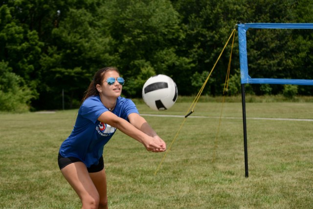 Girl passing volleyball on grass court