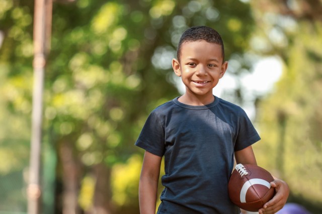 young boy with rugby ball in park