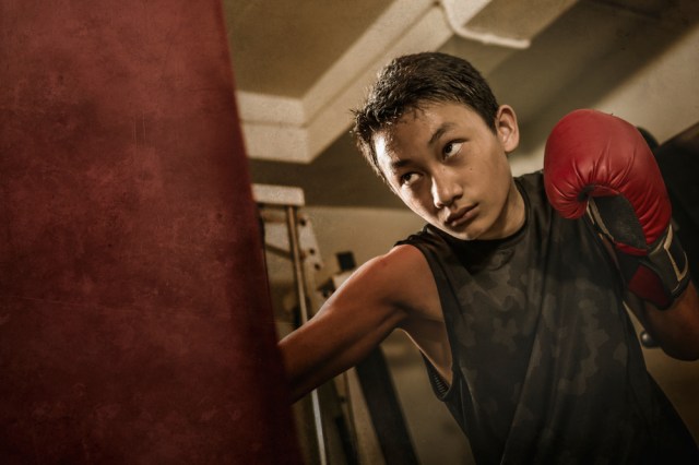 Asian American teenager boxing on gym