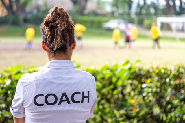 Back view of a female soccer, football, coach in white coach shirt