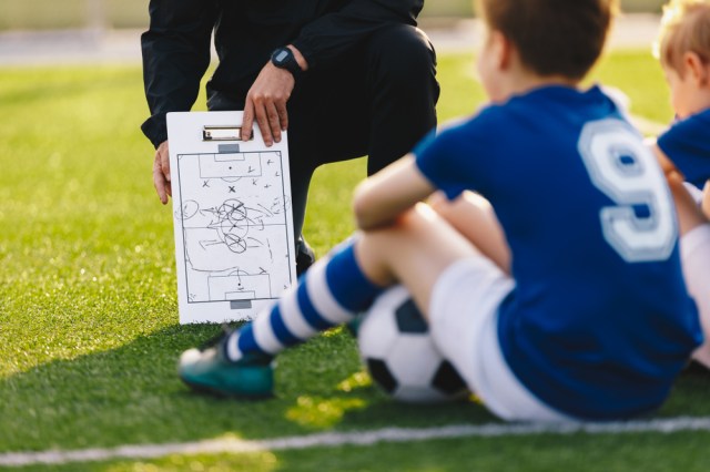 Soccer Team Meeting. Coach Giving Tactic Advices Using Football White Board. Coaching Youth Sports Team