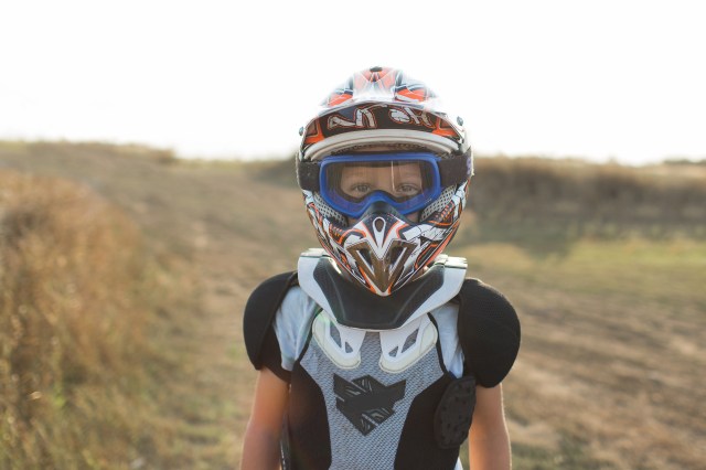 Small biker dressed in a protective suit and helmet.