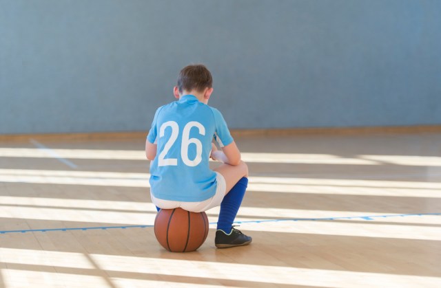 Stressed tired exhausted child with ball in a physical education lesson