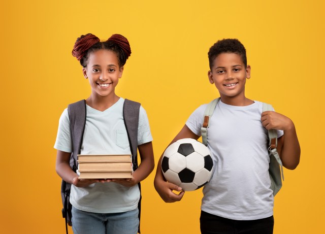 siblings with books and soccer ball