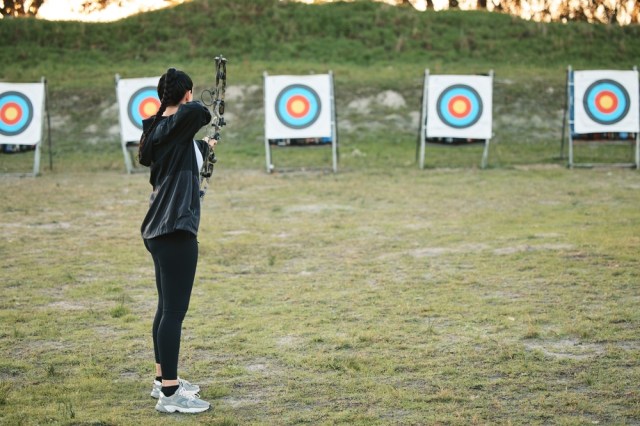Archery practice with targets in background.