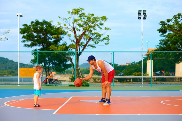 father and son playing basketball on sport ground