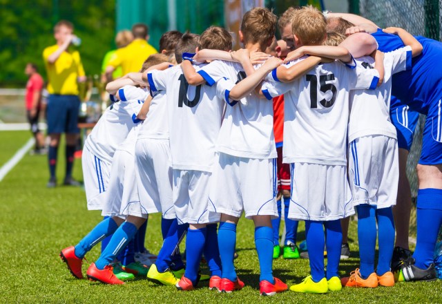Coach giving young soccer team instructions. Youth soccer team together before final game. Football match for children. Boys group shout team, gathering. Coach briefing. Soccer football background.