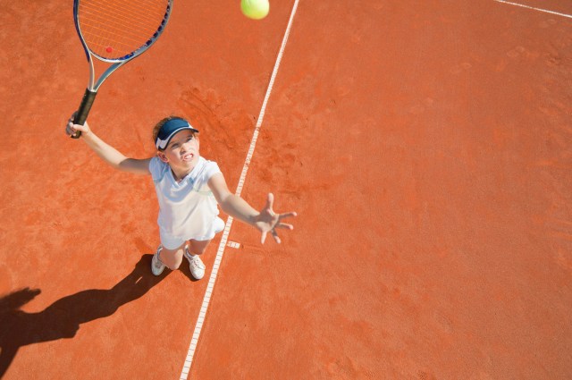 Junior female tennis player on serve.