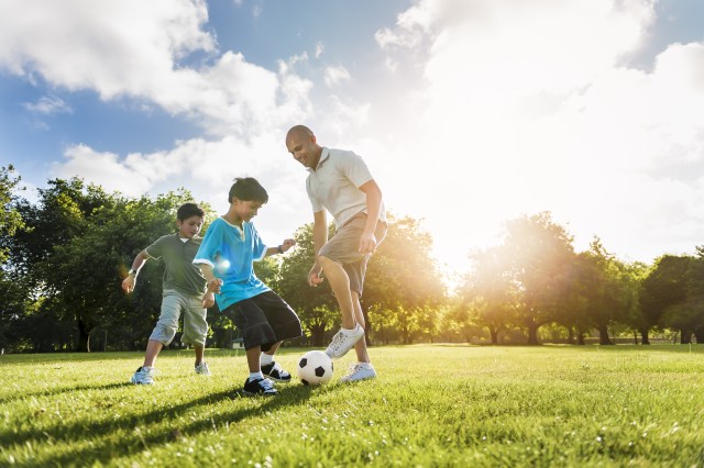 Family playing soccer in the sun
