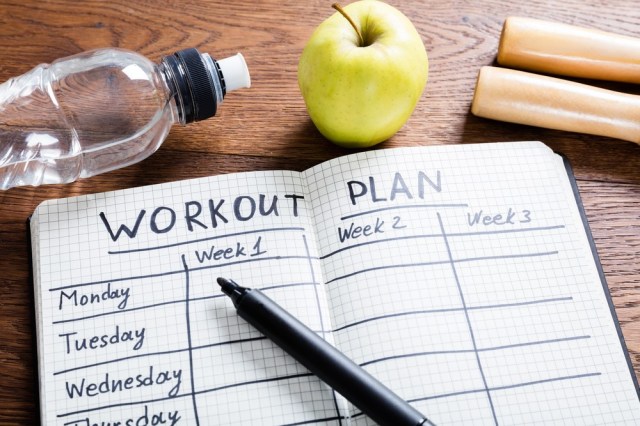 Workout Plan In Notebook At Wooden Desk