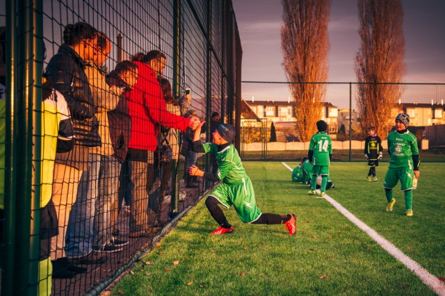 Happy school boy soccer player celebrates victory, shaking hand with his father