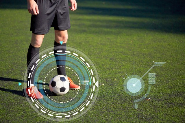 sport, football training and technology - soccer player playing with ball on field