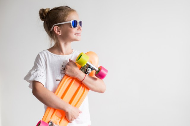 Stylish little girl child with skateboard over white background