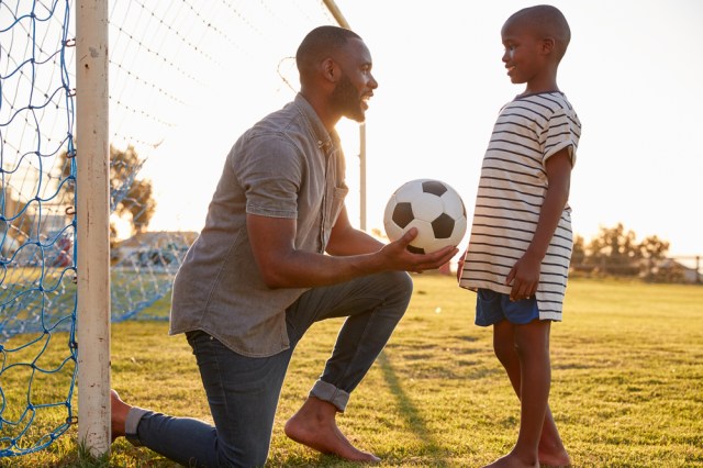 Father gives a ball to his son during a football game