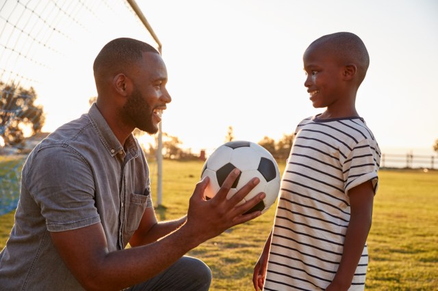 Father gives a ball to his son during a football game