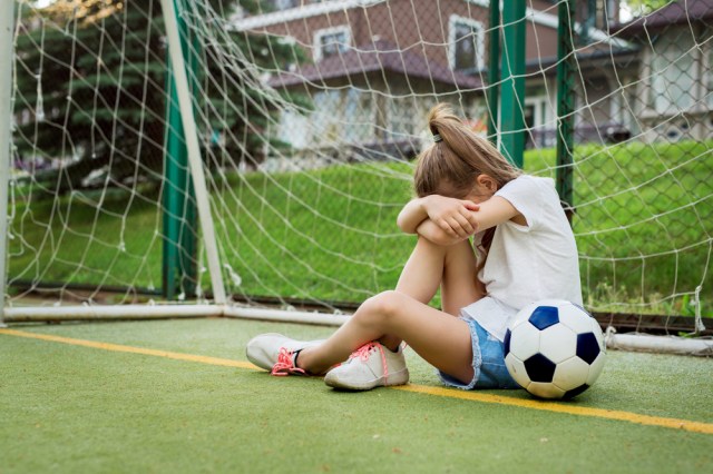 Crying little girl who is playing soccer