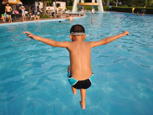 boy jumping into swimming pool