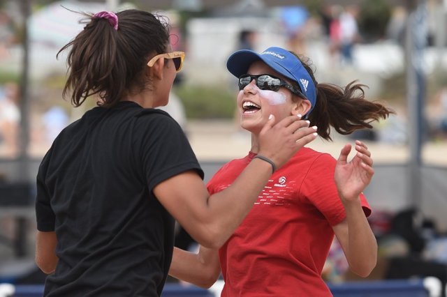 Two female volleyball players playing outside, one with sunscreen on her face