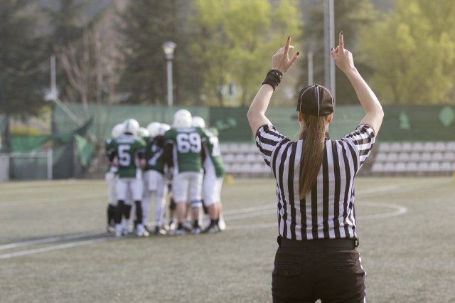 Female American football referee and blurred players in the background